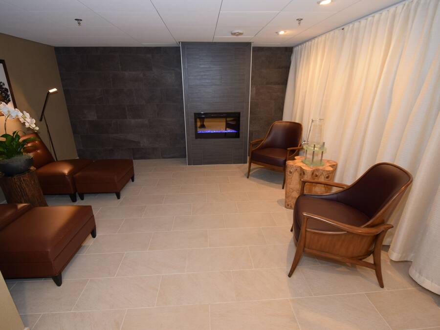 A modern living room with a fireplace, leather sofas, and a wooden chair.