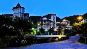 A large, multi-story building with a prominent tower and a well-lit entrance. - Beachfront Hotel (Ho Chi Minh City)