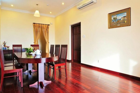 A dining area with a round table, six chairs, and a curtain.