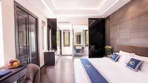 A modern hotel room with a large bed, a desk with a computer, and a view of the outdoors. - Beachfront Hotel (Ho Chi Minh City)