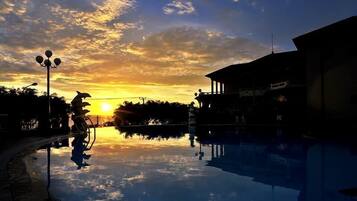 Una piscina al aire libre, sombrillas, sillones reclinables de piscina