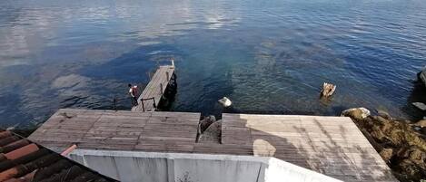 A wooden dock extending into a calm body of water, with a person standing at the end.