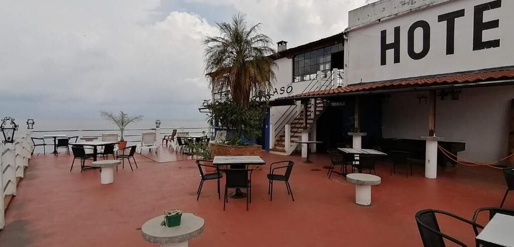 A hotel patio with outdoor seating, a palm tree, and a staircase leading to the entrance.