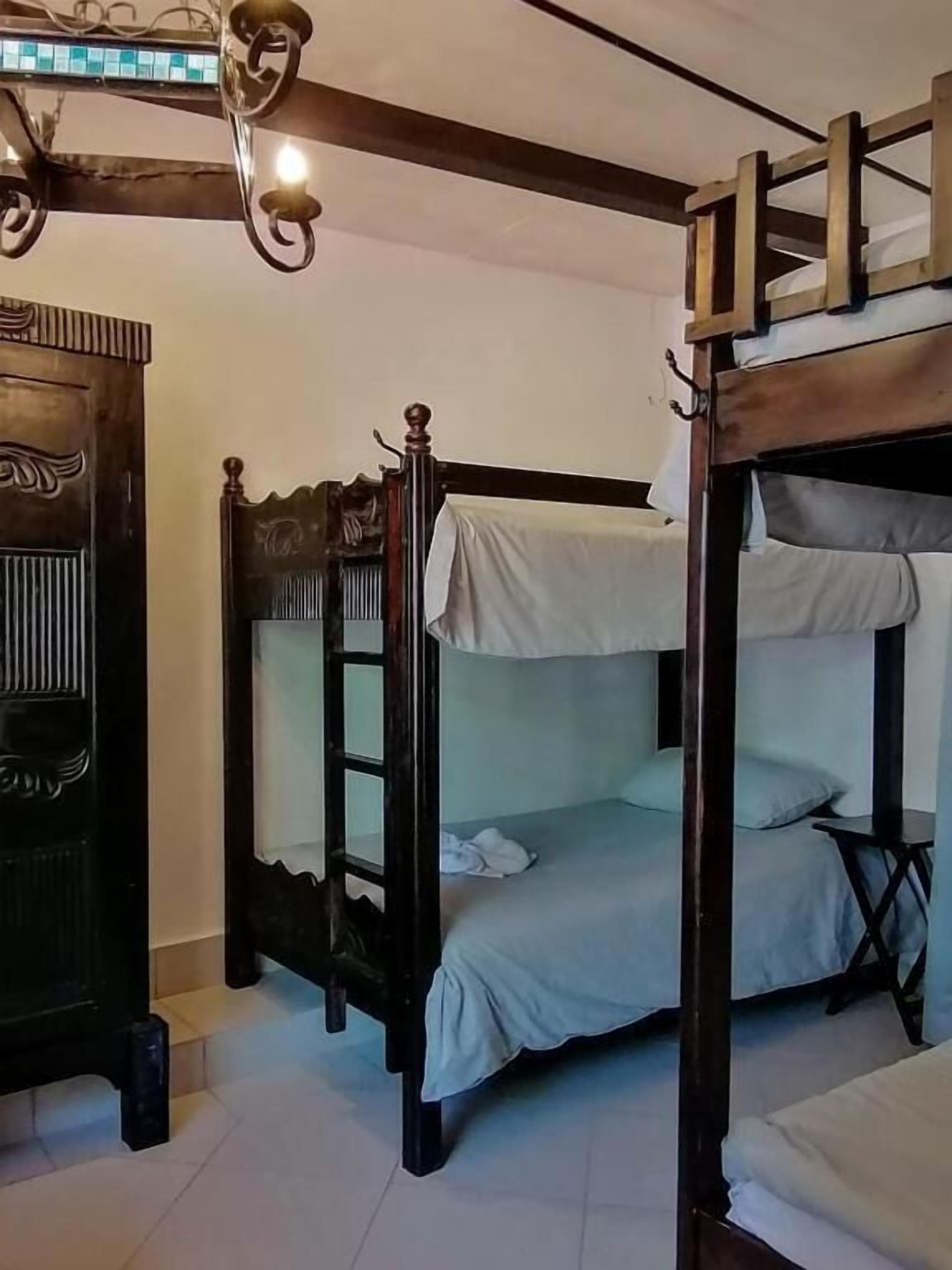 A room with bunk beds, a wooden door with intricate carvings, and a chandelier.