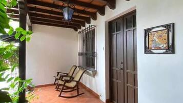 Un patio cubierto con baldosas de terracota, vigas de techo de madera y un conjunto de dos mecedoras.