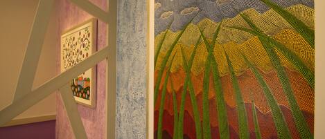 A room with a framed artwork depicting stylized plants and a building.