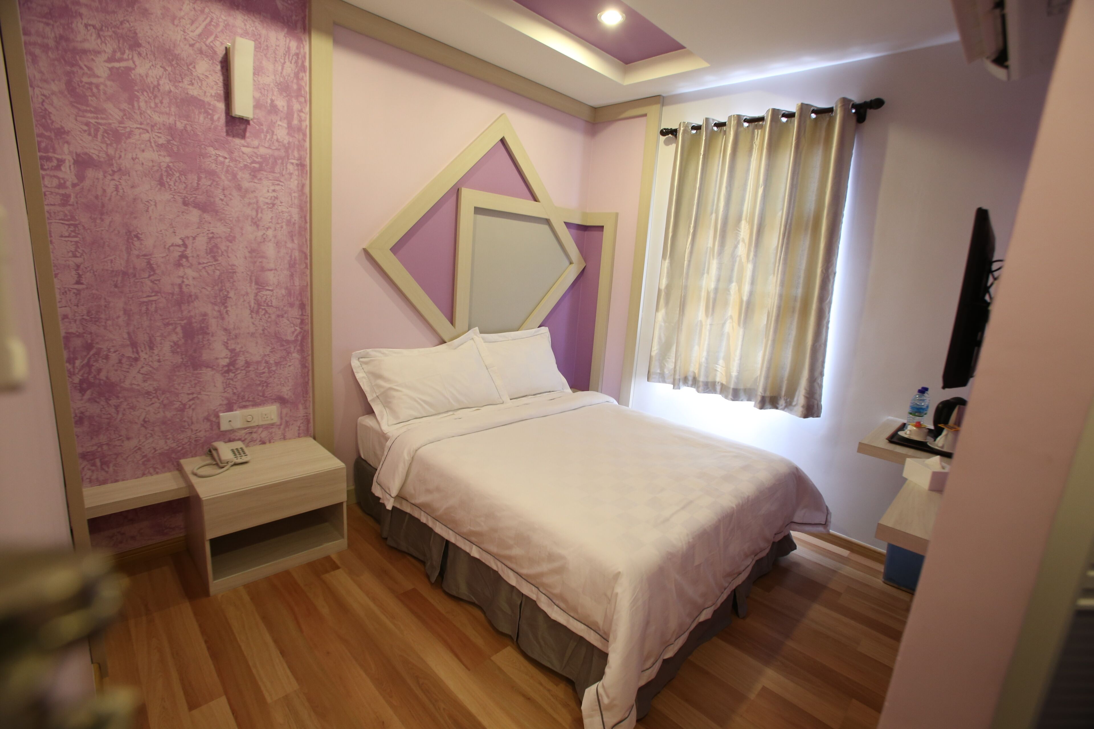 A bedroom with a bed, bedside table, and a small desk with a chair.