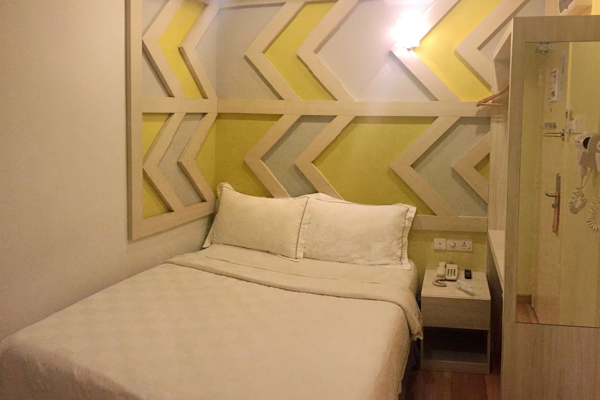 A hotel room with a bed, a nightstand, and a wardrobe.