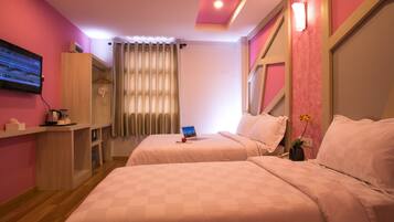 Habitación de hotel con dos camas, un televisor, un escritorio con tetera y una ventana con cortinas.