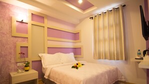 Une chambre à coucher avec un lit, une table de chevet et un téléviseur fixé au mur.