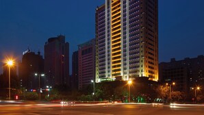 A high-rise building with illuminated signage, multiple floors, and a modern architectural design. - Holiday Inn Express Luoyang City Center by IHG (Luoyang)