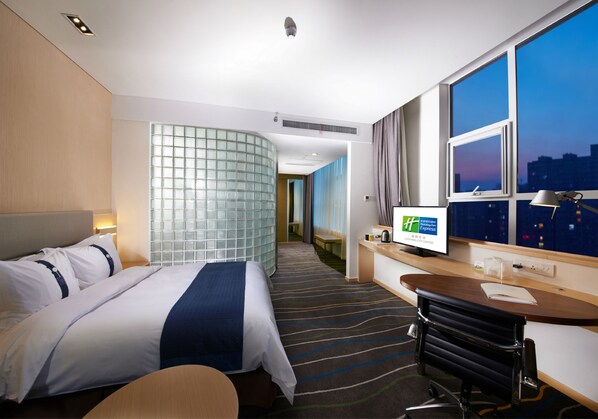 A hotel room with a bed, desk, TV, and large windows with a city view. - Holiday Inn Express Luoyang City Center by IHG (Luoyang)