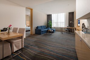 A hotel room with a dining table, two chairs, a sofa, a small coffee table, a TV, a desk, and a large window with curtains. - Holiday Inn Express Luoyang City Center by IHG (Luoyang)