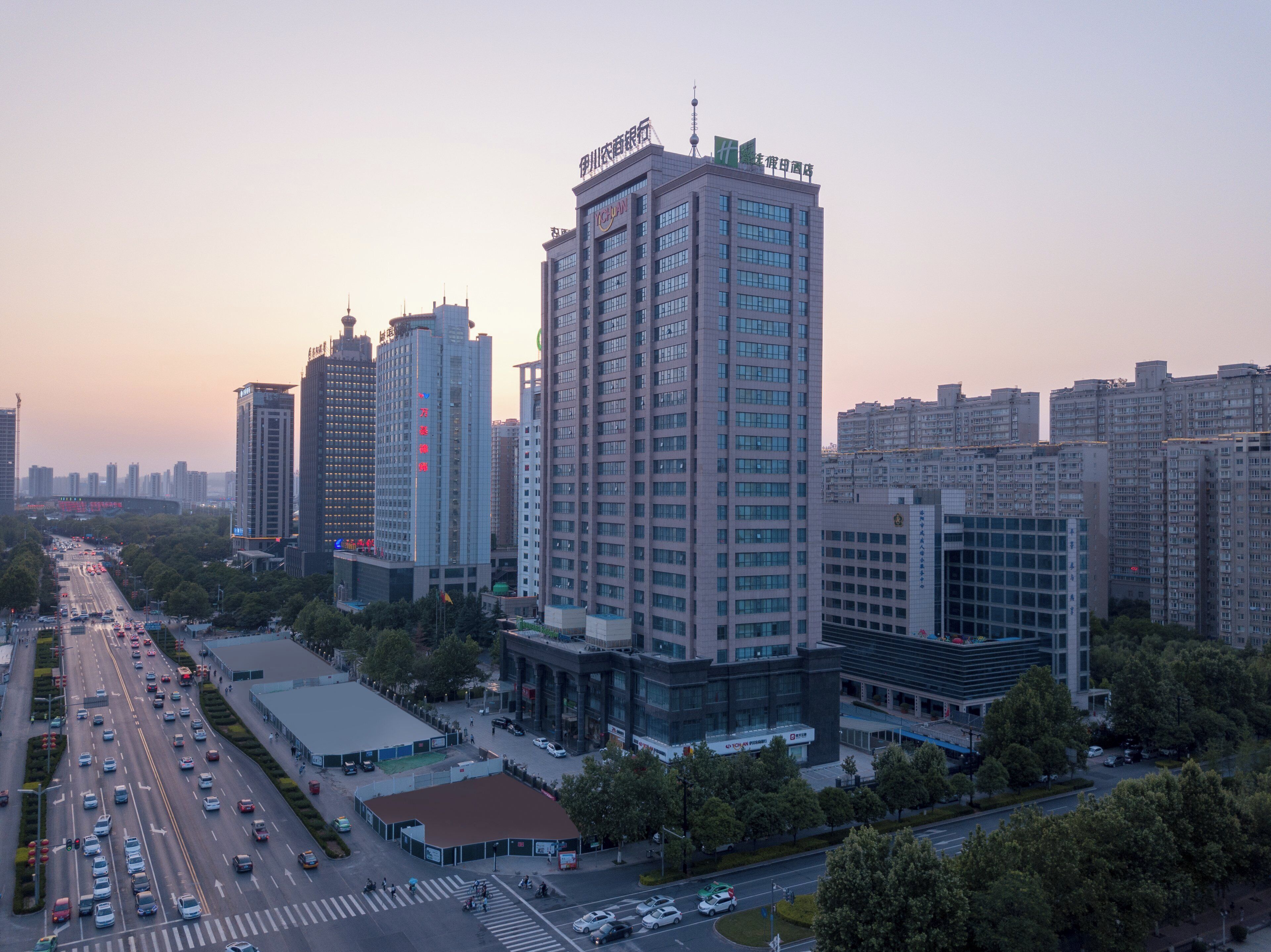 A high-rise building with multiple floors, surrounded by other buildings and a busy street with vehicles.