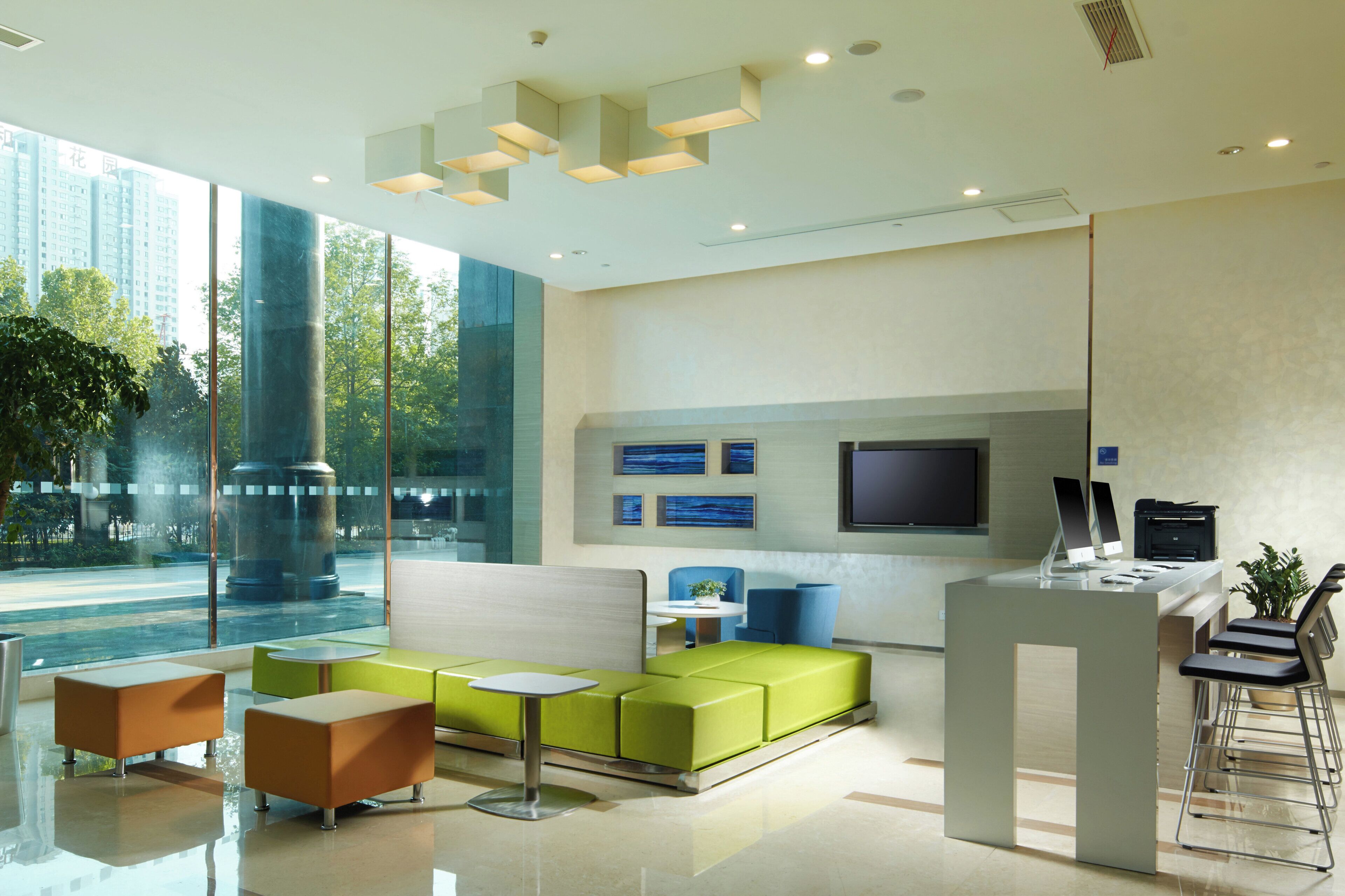 A modern reception area with a seating area, a reception desk, and a large window offering a view of the outdoors.