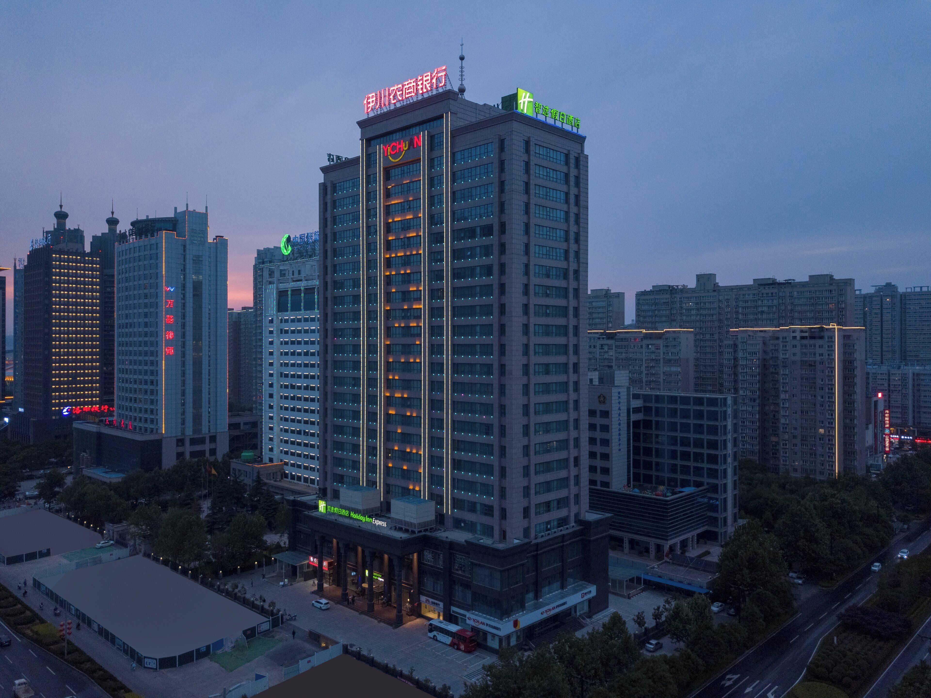 Un hotel moderno de gran altura, con varios pisos, un letrero llamativo en la parte superior y un área de entrada bien iluminada.