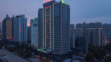 Un hotel moderno de gran altura, con varios pisos, un letrero llamativo en la parte superior y un área de entrada bien iluminada.