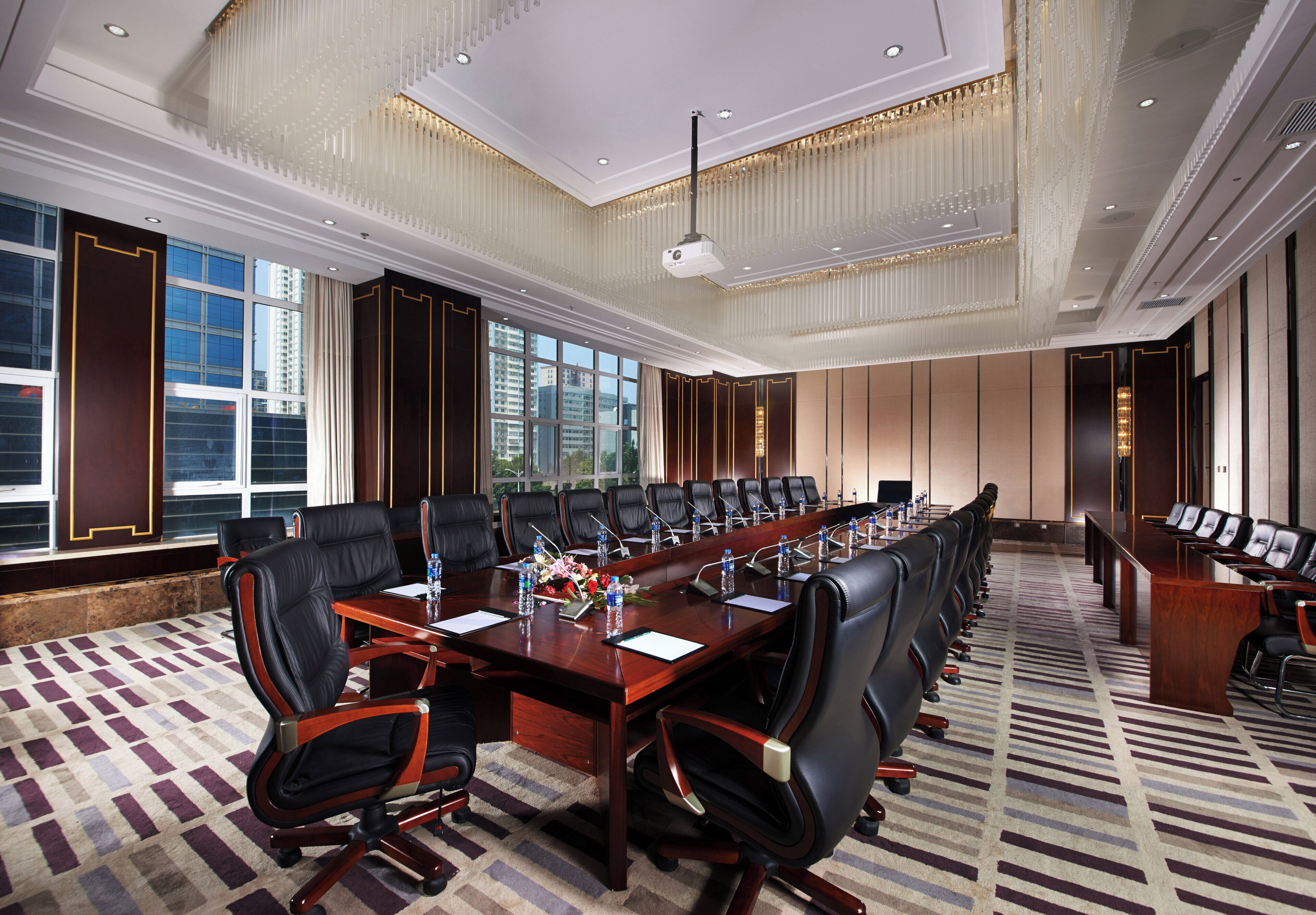 A conference room with a long table, multiple chairs, and a carpeted floor.