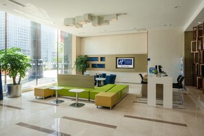A hotel reception area with a modern design, featuring a reception desk, seating area with sofas and tables, and a large window providing a view of the cityscape. - Holiday Inn Express Luoyang City Center by IHG (Luoyang)