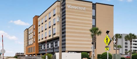 A Wavecrest hotel with a modern facade, multiple balconies, and a pedestrian crossing sign.