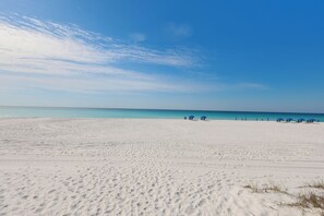 Een strand met voetafdrukken en een heldere lucht.