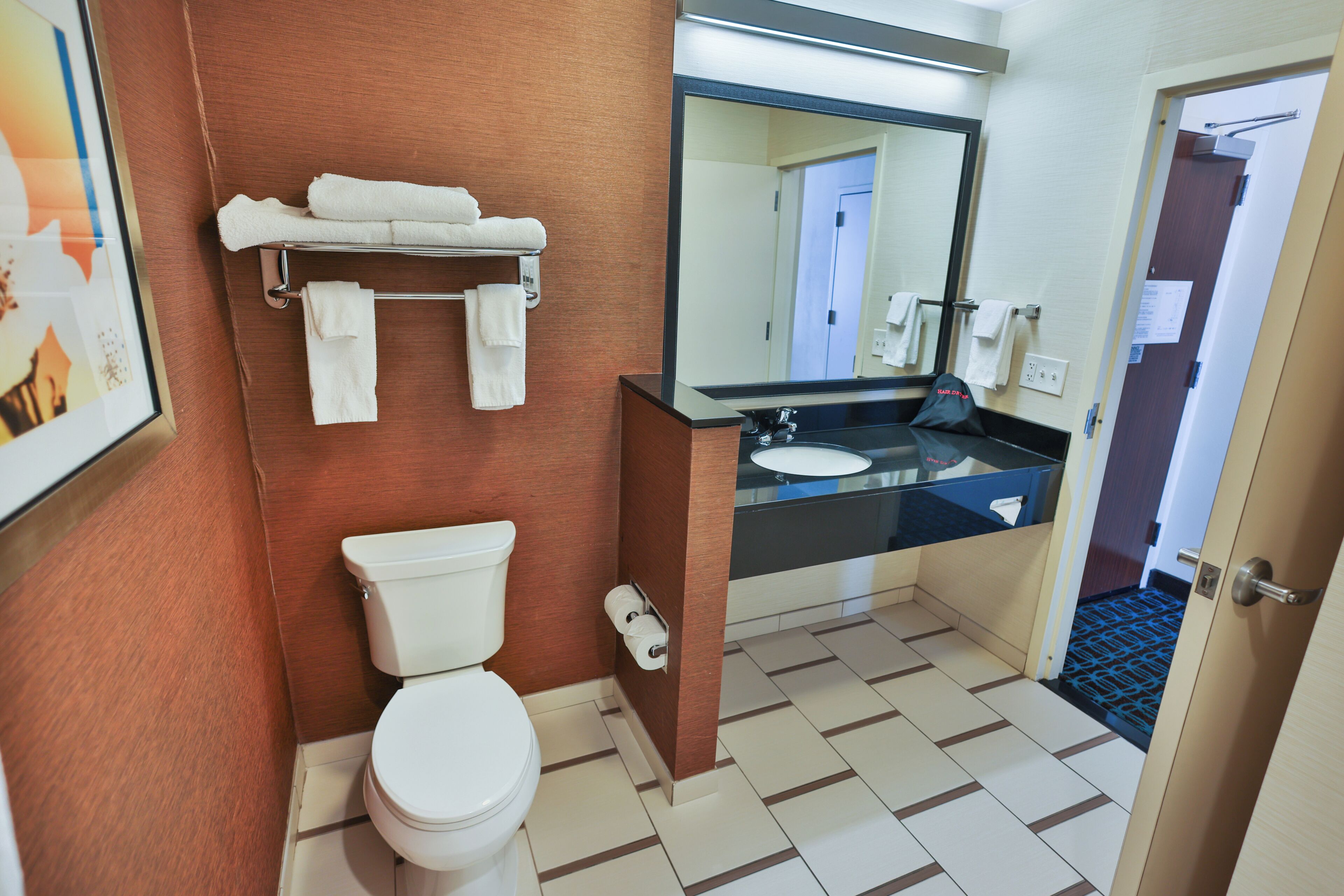 Une salle de bain équipée d’un WC, d’un lavabo, d’un miroir et d’un porte-serviettes.