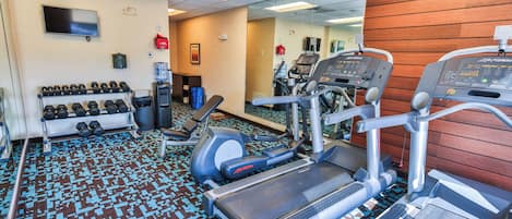 A gym with treadmills, dumbbells, and a water cooler.