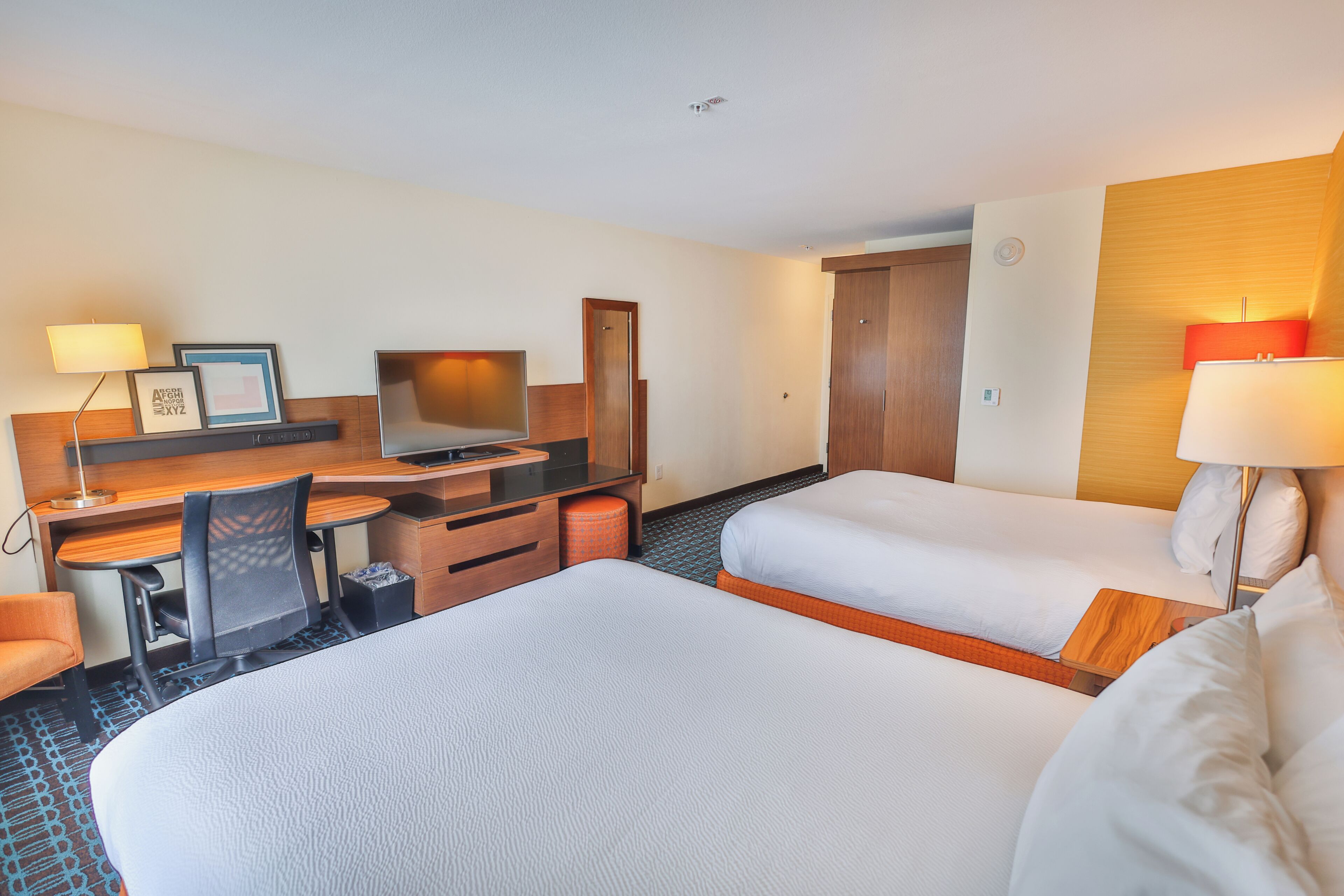 Una habitación de hotel con cama, escritorio, silla y dos lámparas de noche.