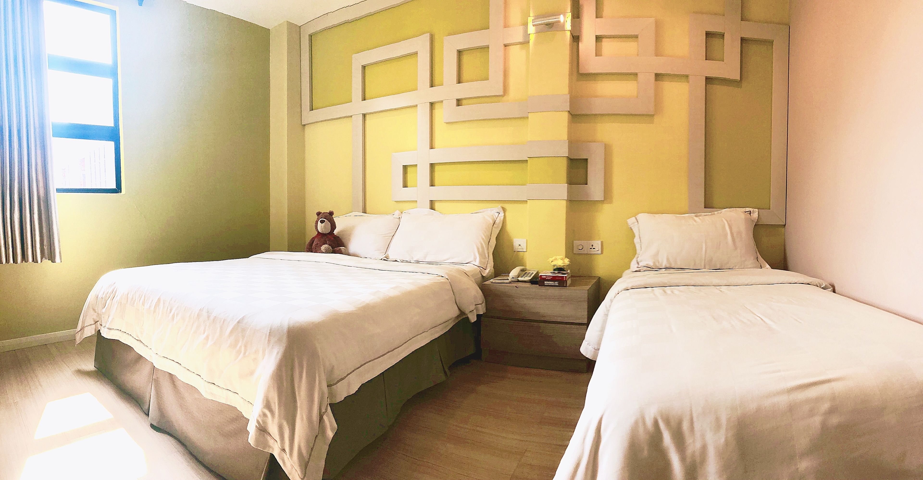 A hotel room with two beds, a nightstand, and a wall with geometric patterns.