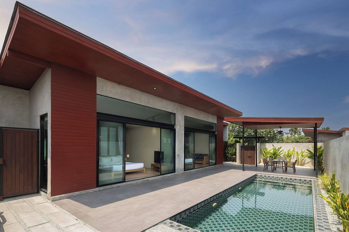 Une maison moderne dotée d’une piscine, de grandes portes vitrées et d’un patio couvert.