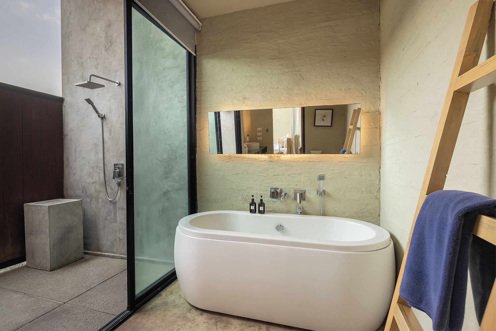 A modern bathroom with a freestanding bathtub, a glass shower enclosure, and a large mirror above the sink.