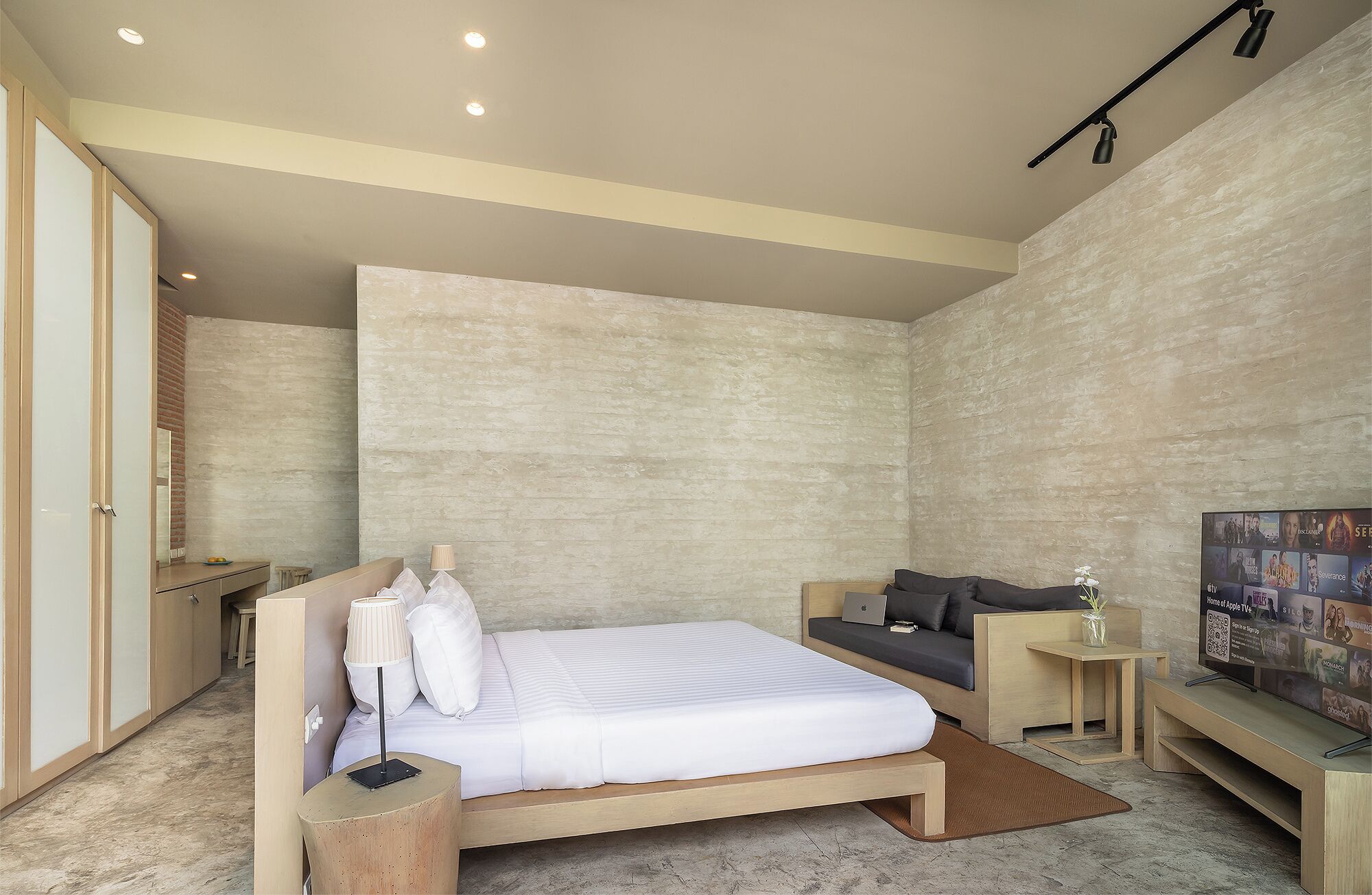 A modern bedroom with a bed, bedside tables, a sofa, and a TV.