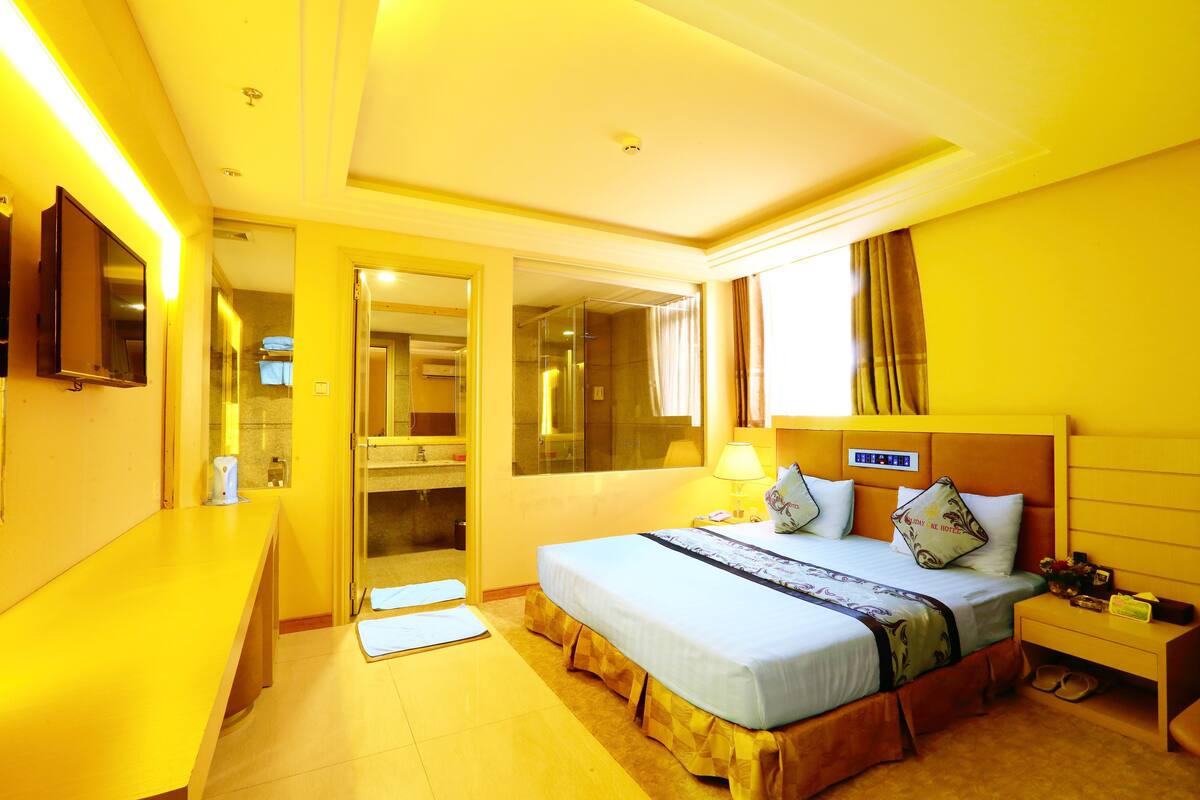 Une chambre d’hôtel avec un lit, une table de chevet, une lampe et un miroir.