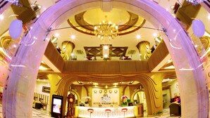 A hotel lobby with a reception desk, a chandelier, and a large arched entrance. - Holiday One Hotel (Can Tho)