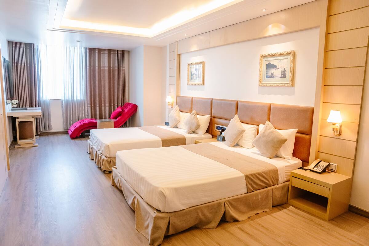 Une chambre d’hôtel avec deux lits, un bureau, une chaise et une table de chevet avec un téléphone.