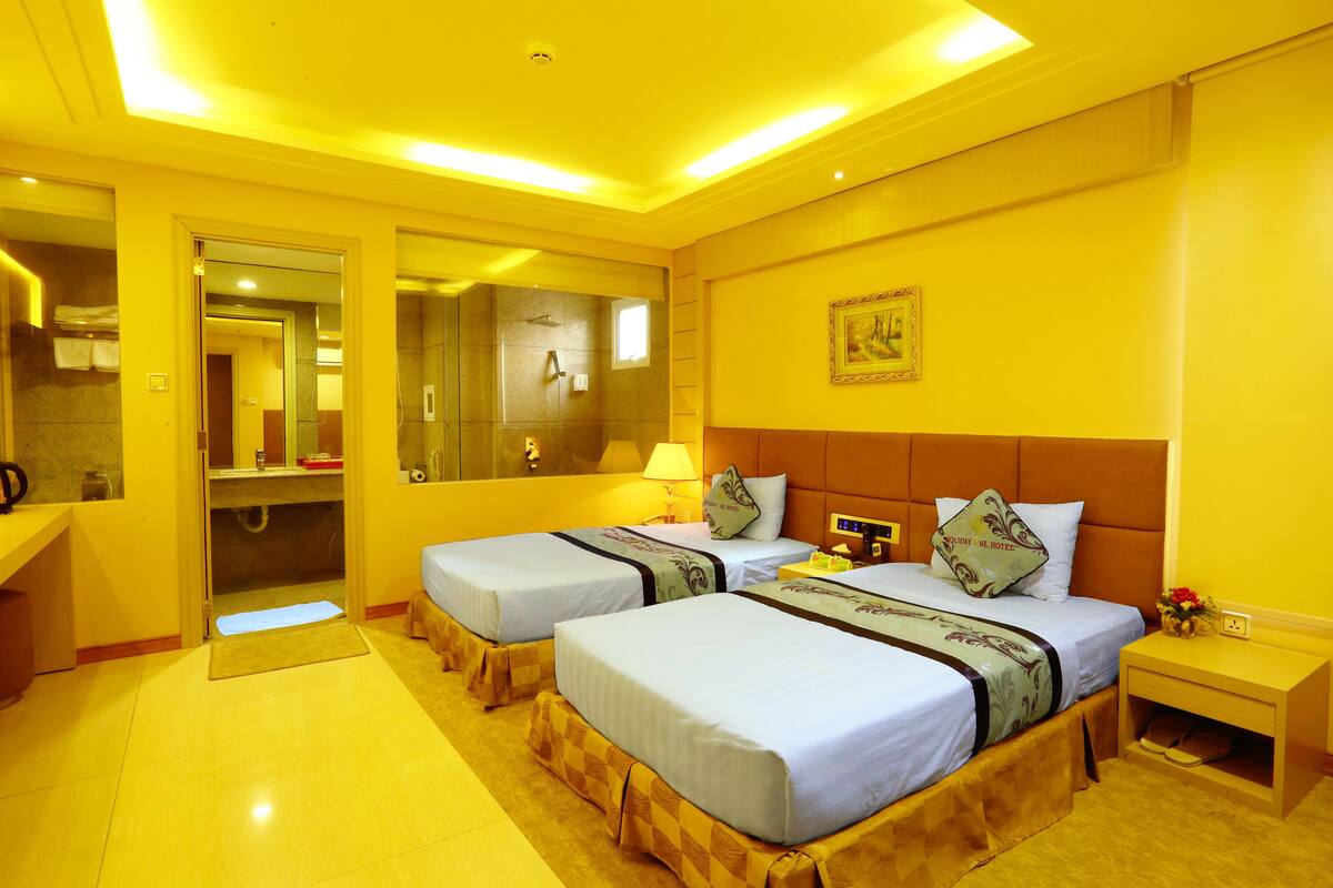 Une chambre d’hôtel avec deux lits, une salle de bain et un petit espace bureau.