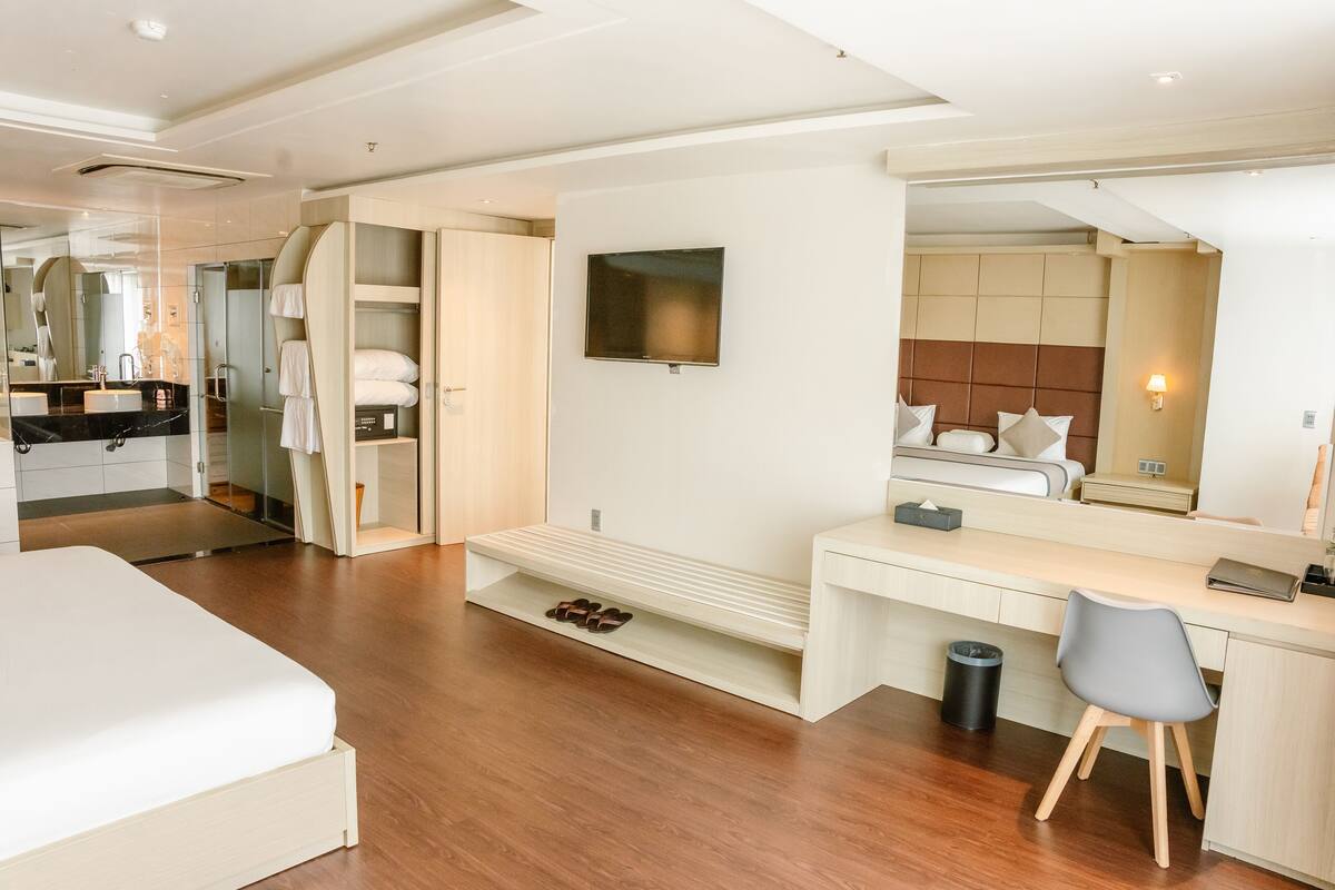Une chambre d’hôtel moderne équipée d’un lit, d’un bureau, d’une télévision, d’une salle de bain et d’un espace douche.