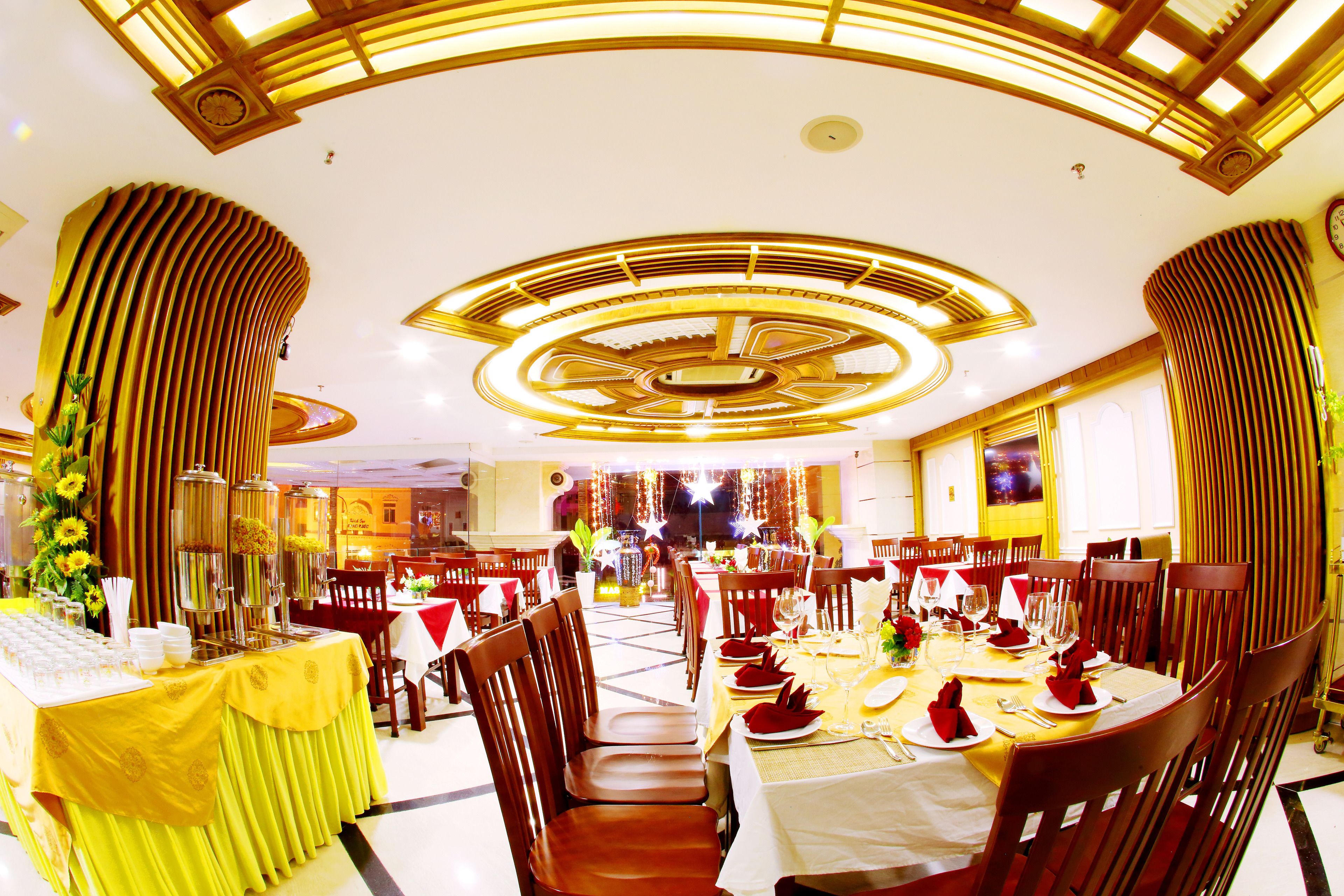 A restaurant with a high ceiling, circular chandeliers, and a central dining area with tables set for multiple guests.