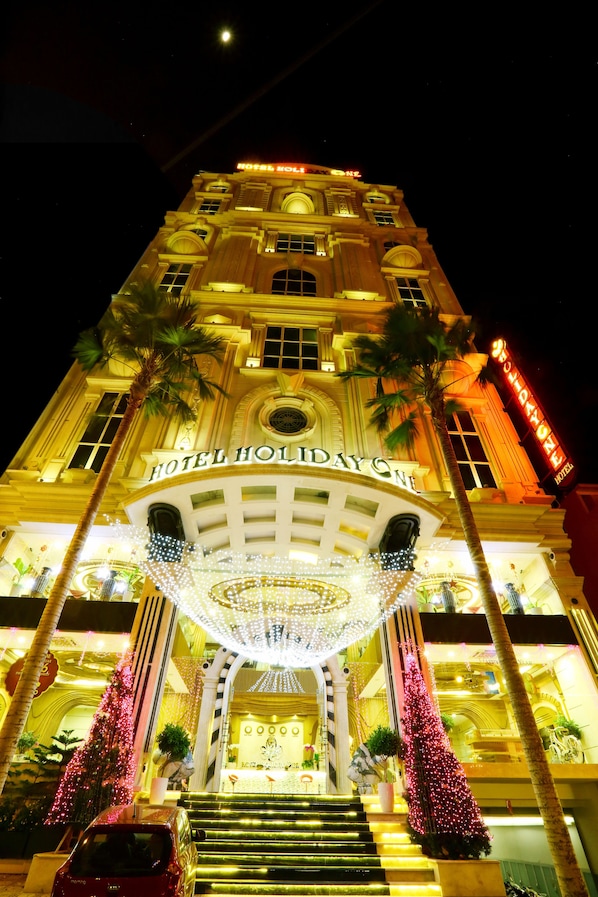 Ein Hotel mit einem imposanten Eingang, einer Treppe zum Empfangsbereich und Palmen.