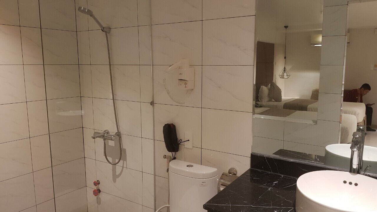 A bathroom with a shower, toilet, sink, and a large mirror.