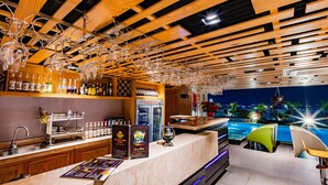 A bar area with wooden ceiling beams, a pool table, and a view of the city at night. - Holiday One Hotel (Can Tho)