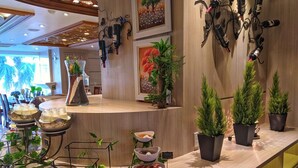 A buffet setup with various food items and decorative plants. - Holiday One Hotel (Can Tho)