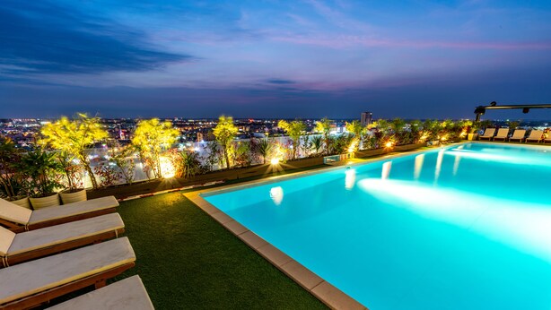 A swimming pool with a view of a cityscape at dusk. - Holiday One Hotel (Can Tho)