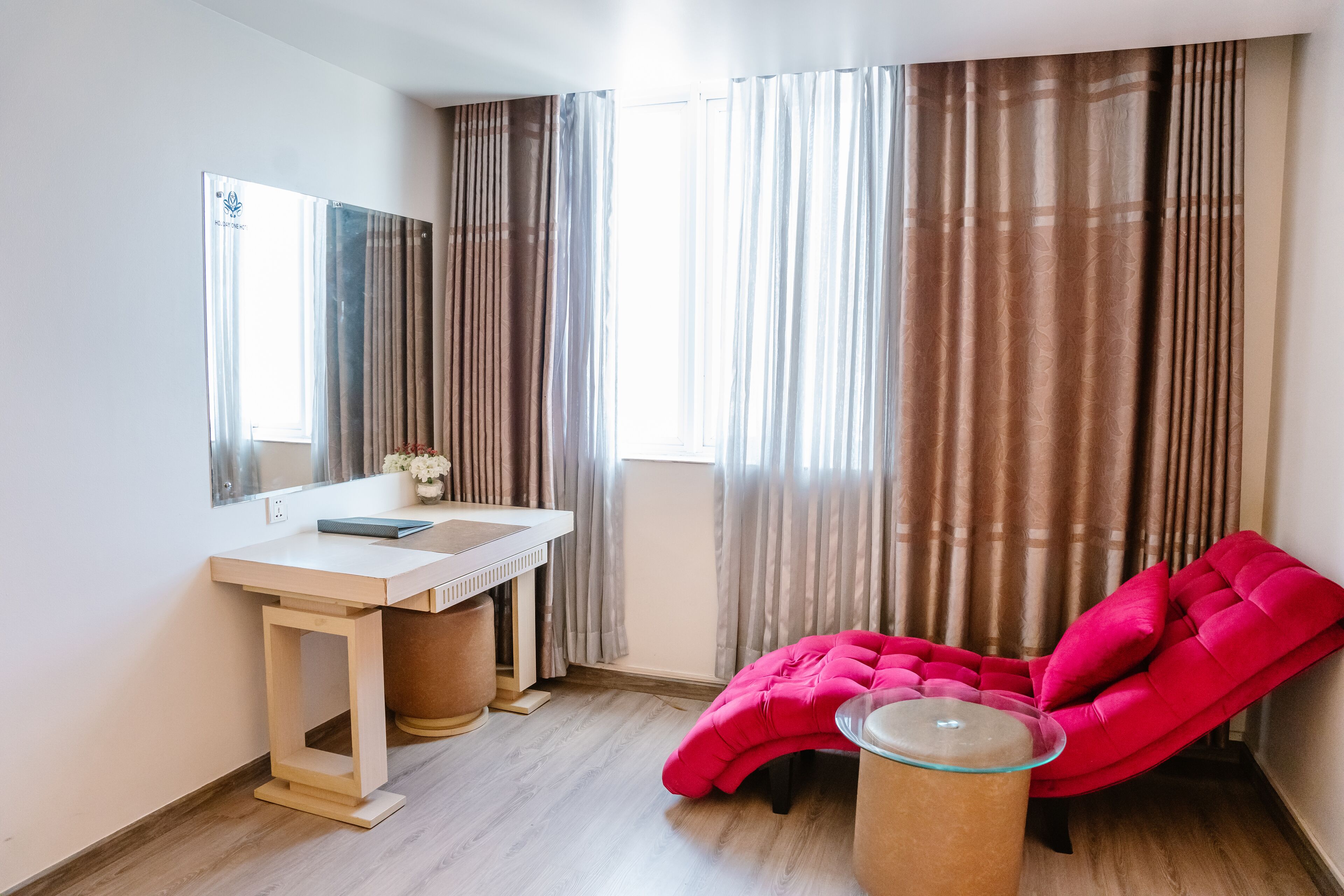 Un baño moderno con tocador de madera, un espejo grande y una silla tapizada en rojo.