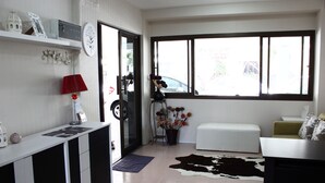 A modern living room with a white sofa, a black and white cowhide rug, a red lamp, and a large window with a view of the outside. - The European Place (Bangkok)