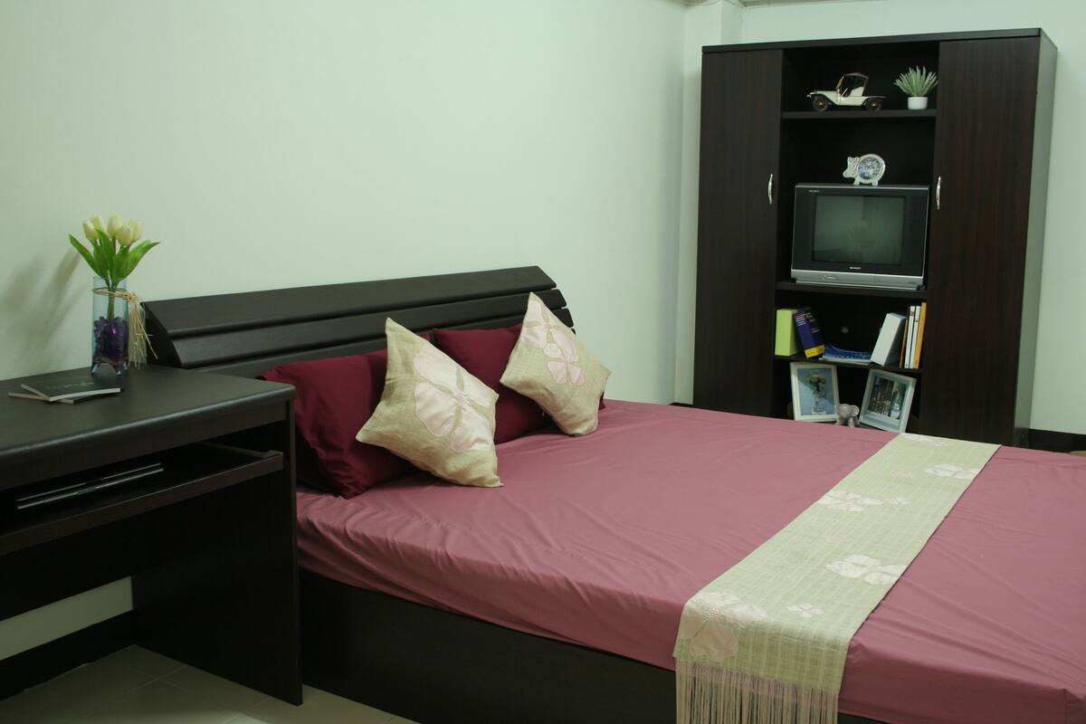 A bedroom with a bed, a desk, and a wardrobe.