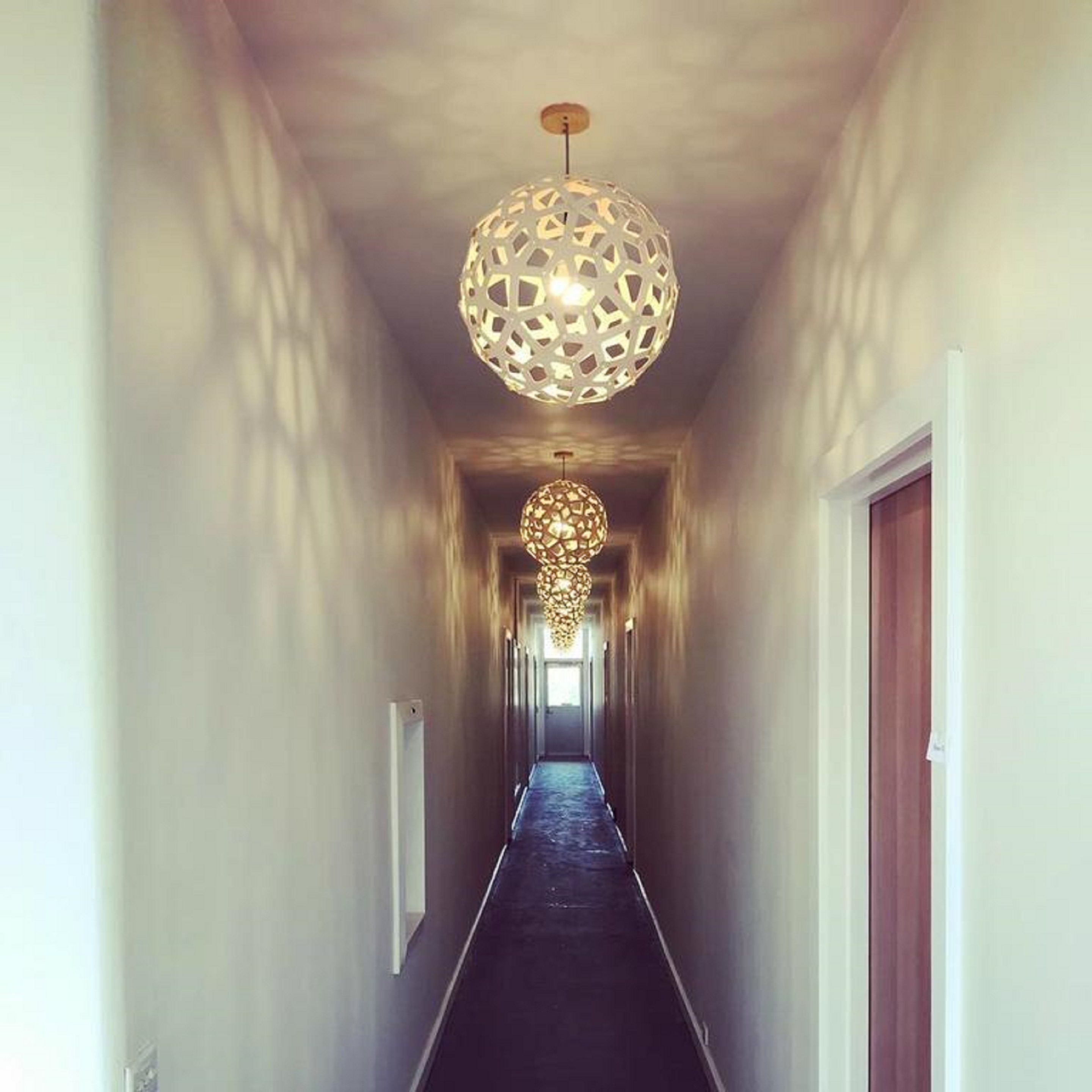 Um corredor com luminária no teto com padrão decorativo e uma porta à direita.