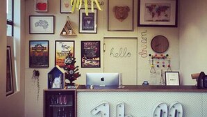 A reception desk with a 'Hello' sign, framed artwork on the wall, and a clock. - Blue Hills Motel (Battery Point)