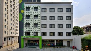 A hotel with a modern facade, multiple floors, and a green entrance. - Zodiak MT Haryono by KAGUM Hotels (Jakarta)