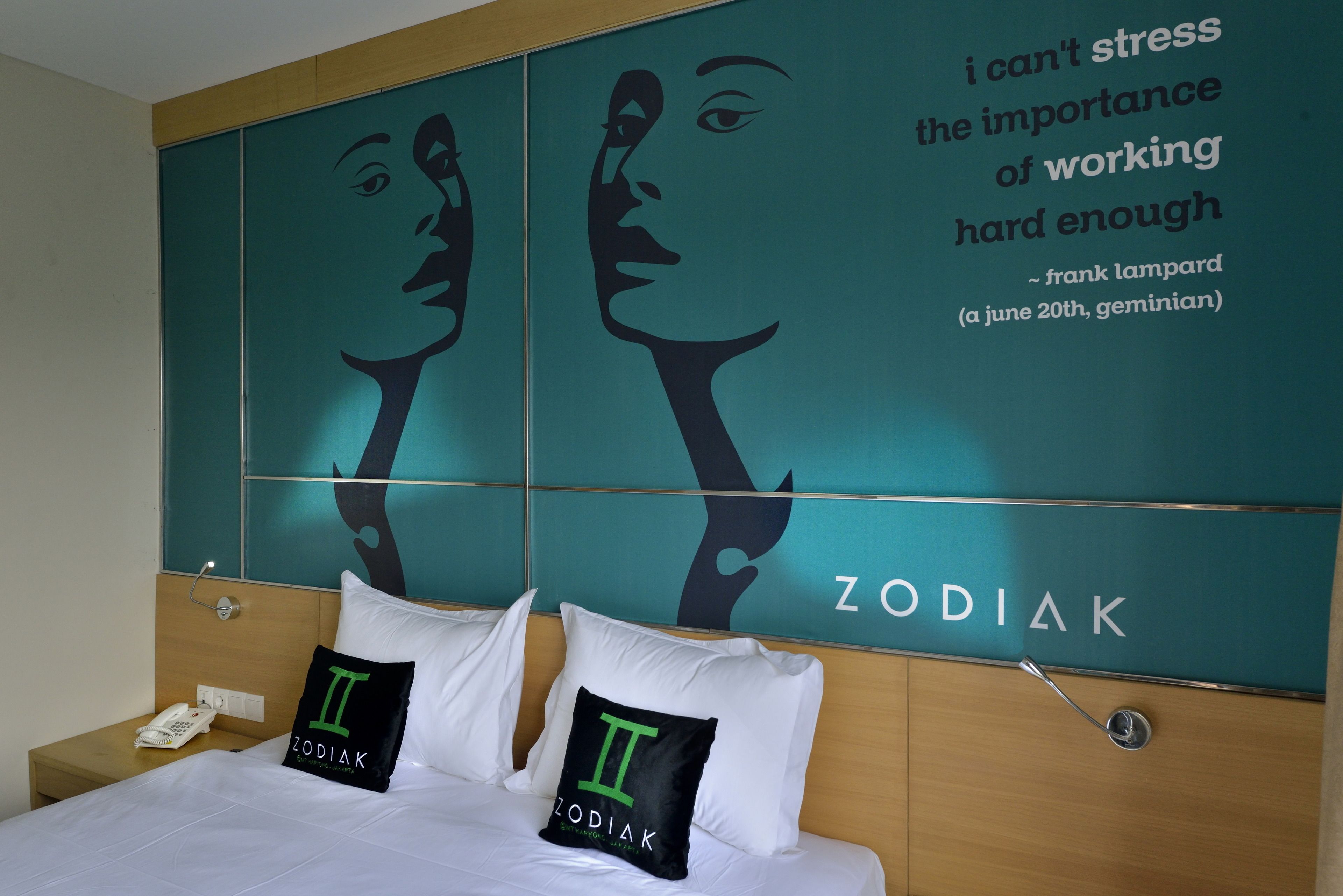 Habitación de hotel con un mural grande que muestra una cita y signos del zodiaco.